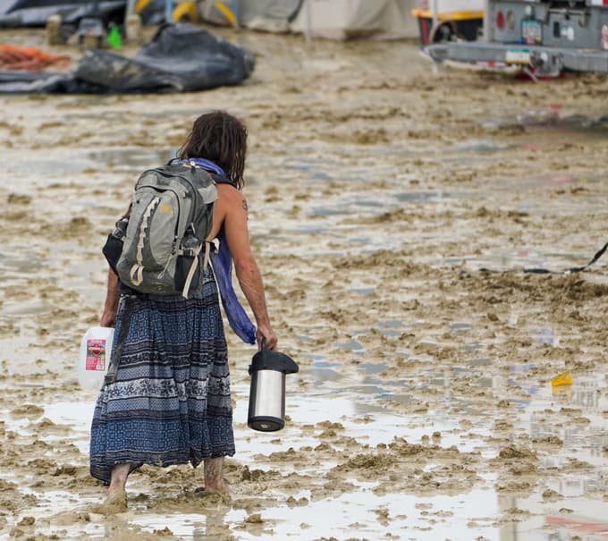 Udeleženka festivala se prebija prek blata.