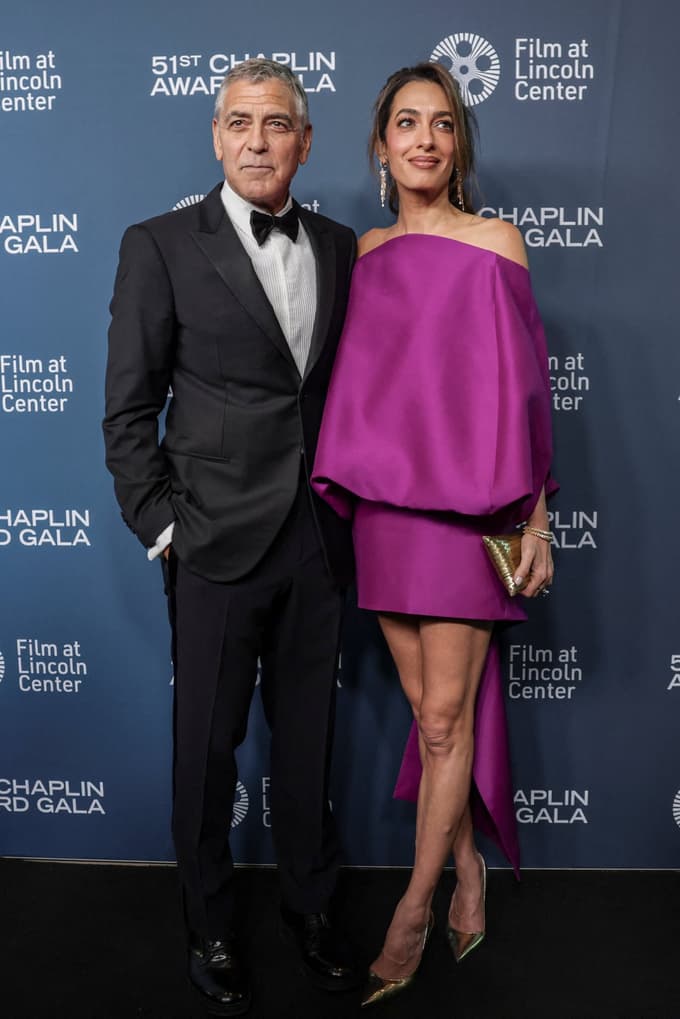 Obleka ima spuščen izrez, ki odkriva ramena, in voluminozne balonaste rokave, ki ustvarjajo dramatično, zaobljeno obliko. Krilo je izrazito kratko in poudarja njene dolge noge. 