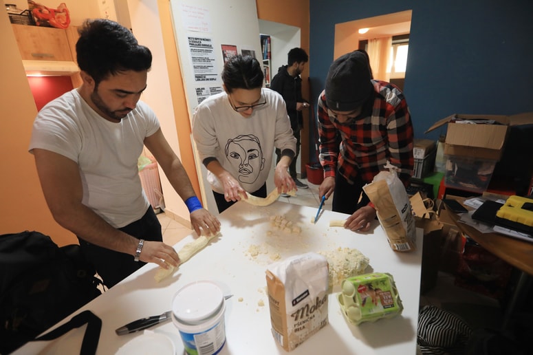 Vsak dan nekdo iz skupnosti skuha kosilo. V torek je ta naloga pripadla Ani, pomagala pa sta ji dva begunca. Foto: Robert Balen
