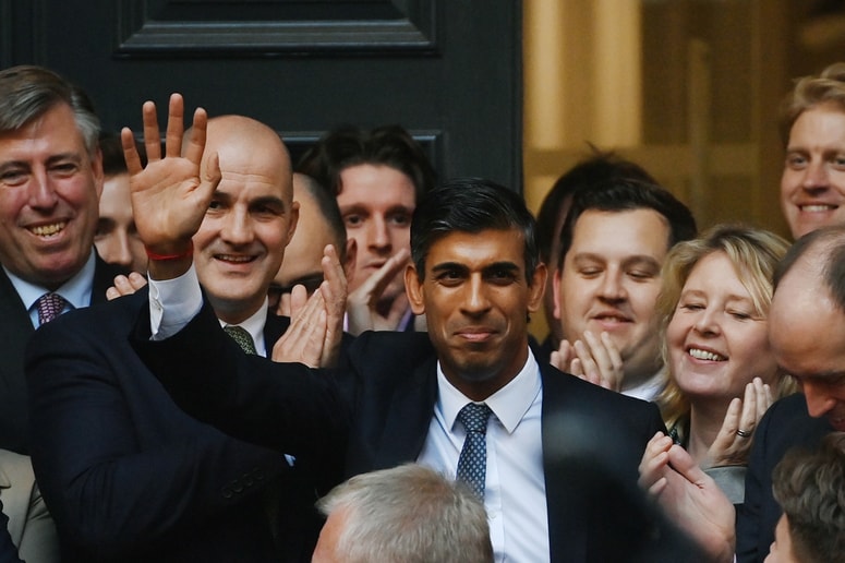 Rishi Sunak z roko, dvignjeno v pozdrav, med navdušenimi torijci ob prihodu na sedež konservativne stranke v Londonu 