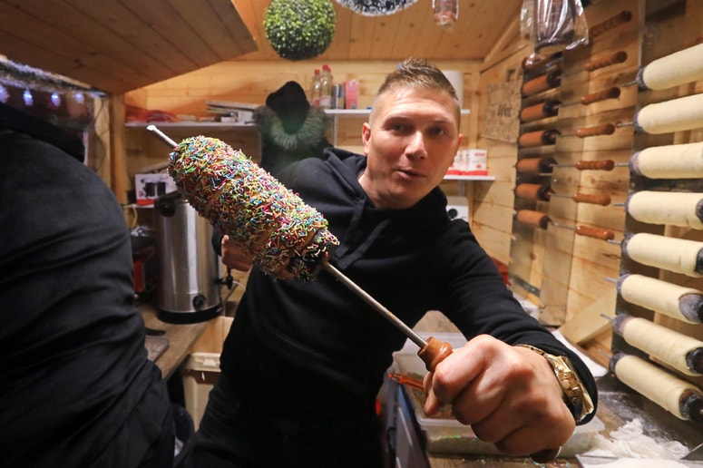 Ne vrti se na Glavnem trgu samo kolo, temveč tudi vroči kurtoši. Josip Galešič jih še vroče marljivo posipava, tudi s pisanimi mrvicami. 