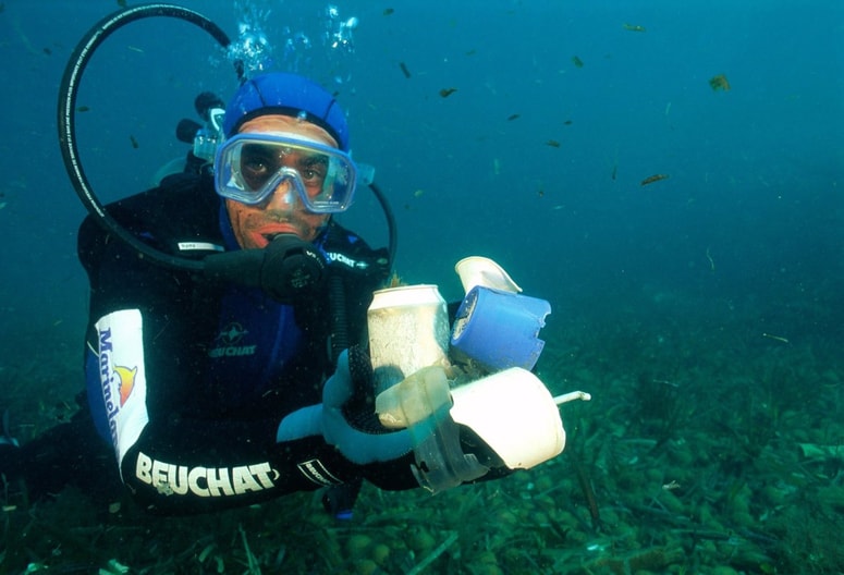 Potapljač drži v roki smeti, ki jih je našel na dnu mediteranskega morja. 