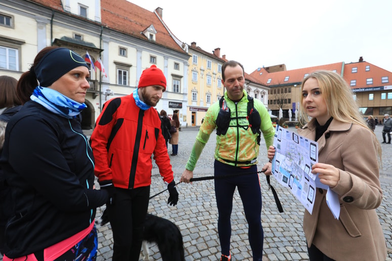 Lara Cafuta predstavlja udeležencem zemljevid, ki jih vodi po dogodivščinah.