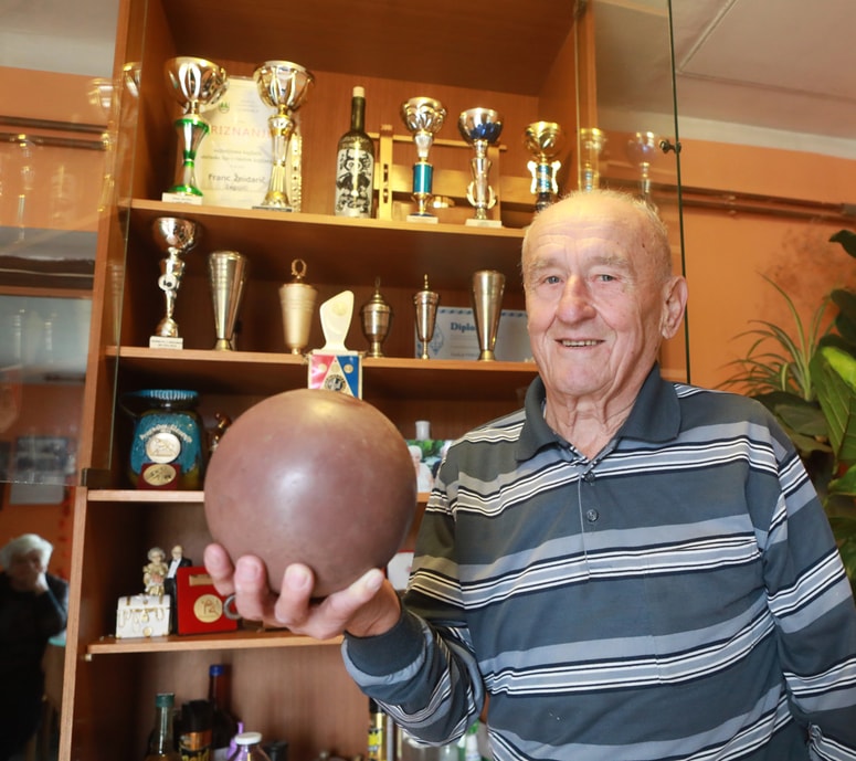 Franc Žnidarič s kroglo in priznanji, ki ga spominjajo na uspešno športno pot 