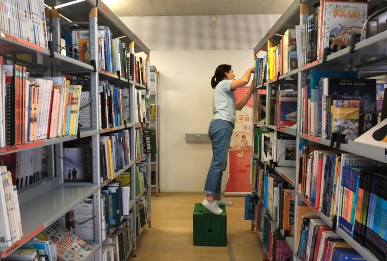 Knjižničarji v dnevih po poplavah gradivo v bibliotekarskem redu razporejajo po policah. 