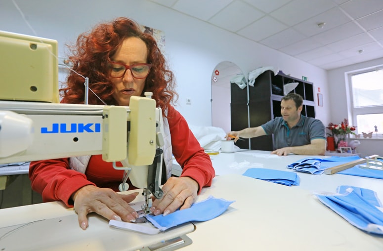 Renata Brdnik samoiniciativno šiva maske, ki jih podarja ljudem, pri delu ji pomaga soprog, ki poreže nitke. 