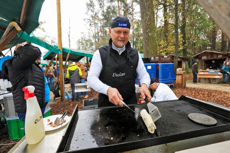 Dušan Krivec, kuhar "na klic", med pripravo hrane na Pohorski tržnici, kjer njegov sin ponuja posebne napitke. 