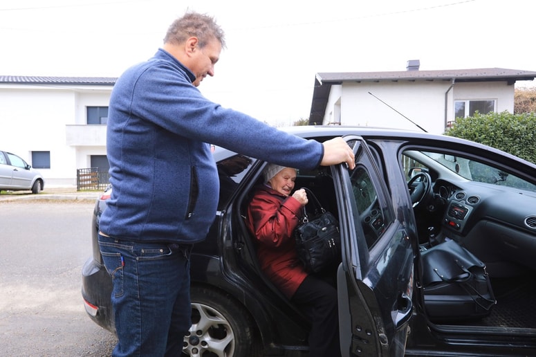 Prostofer Silvo Pongrac pomaga Zori Urek do avtomobila. 