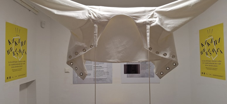 Prisilni jopič z razstave v trafiki v Mariboru. Za umirjanje ljudi se ne smejo več uporabljati, so pa še zmeraj močan simbol totalnih institucij. 