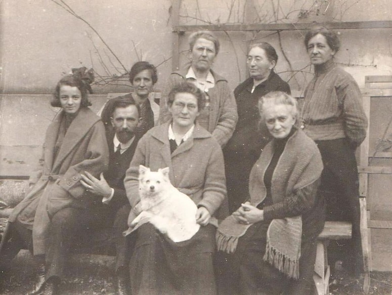 Družina Šantel s prijatelji pred hišo v Vrbanski ulici 62 v Mariboru. Od leve proti desni sedijo: Vojica in Saša Šantel, Božena Sernec s psičkom, Avgusta Šantel st.; v drugi vrsti: Avgusta Šantel ml., učiteljici Nowak (?) in Herman (?) z mornariške šole v Pulju ter Henrika Šantel 