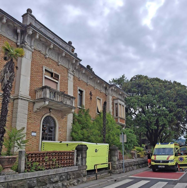 Pod zapuščeno stavbo so gasilci namestili blazino, če bi moški skočil. 