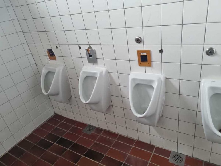 Sanitarije s poškodovanimi električnimi ohišji nad pisoarji 